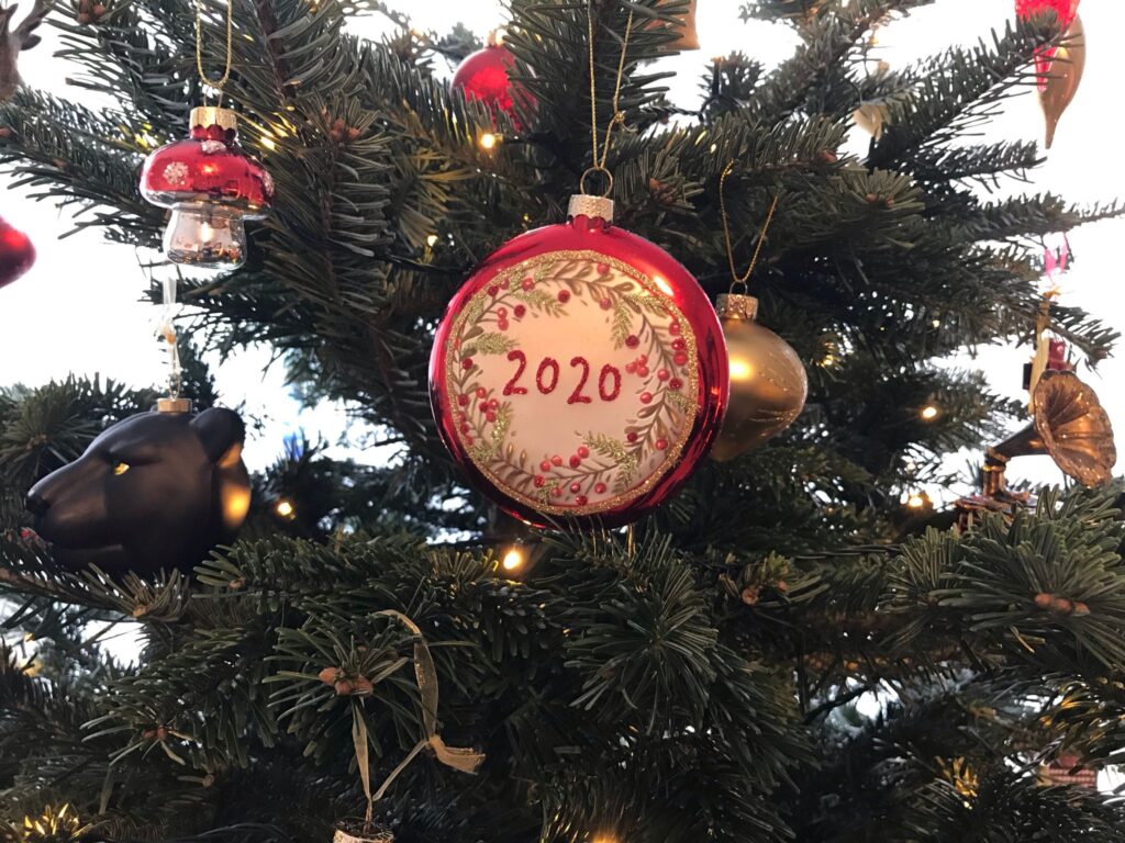 A bauble hanging on a Christmas tree with the year "2020" on it